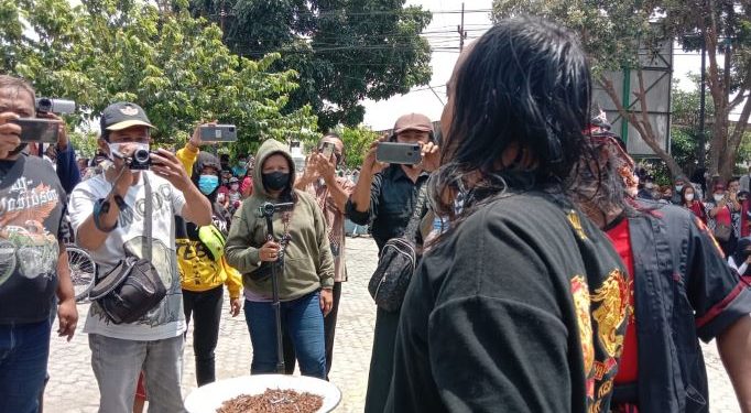 Aksi seniman makan paku disela-sela aksi di Halaman Kantor Kecamatan Pesantren (Kintan Kinari Astuti)