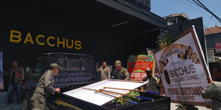 Anggota Satpol PP terlihat mengamankan ucapan berupa karangan bunga di halaman depan Bacchus (Sigit Cahya Setiawan)